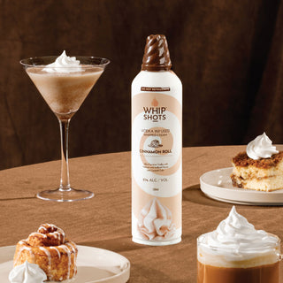 Bottle of Whip Shots Cinnamon Roll with a cocktail and dessert on a wooden surface
