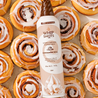 Vodka-infused whipped cream bottle labeled 'Whip Shots' on a tray of cinnamon rolls.