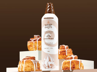 Whip Shots cinnamon roll-flavored whipped cream bottle with cinnamon rolls on a brown background